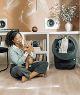 Whisker.com cat using Litter-Robot EVO near woman and orange tabby