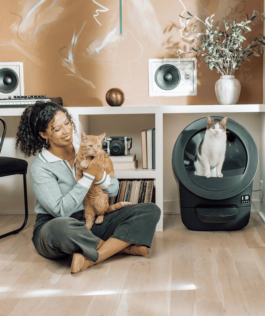 Whisker.com cat using Litter-Robot EVO near woman and orange tabby